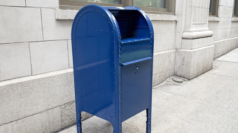 Unmarked blue mailbox on city street