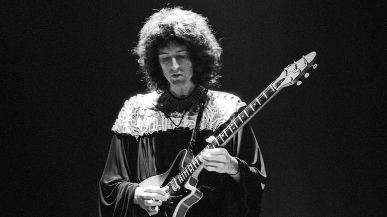 Brian May onstage with guitar under spotlight