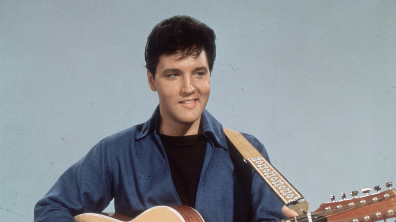 Elvis Presley smiling and playing guitar