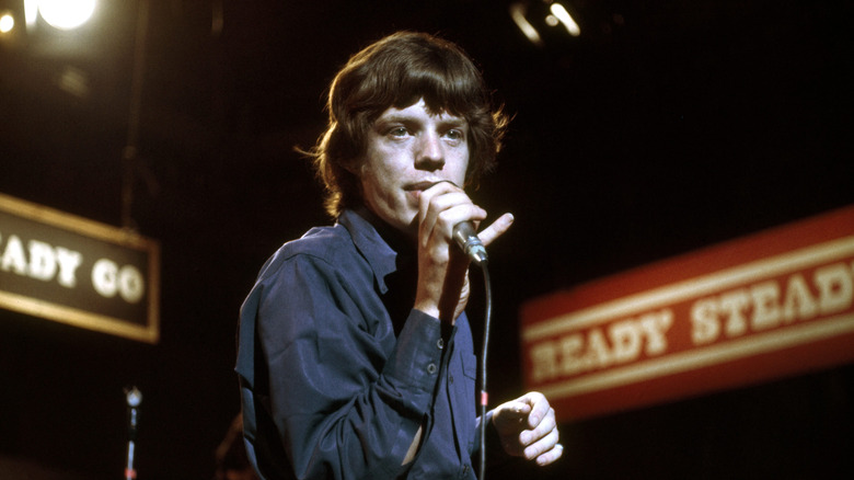 Mick Jagger performing on stage in blue shirt