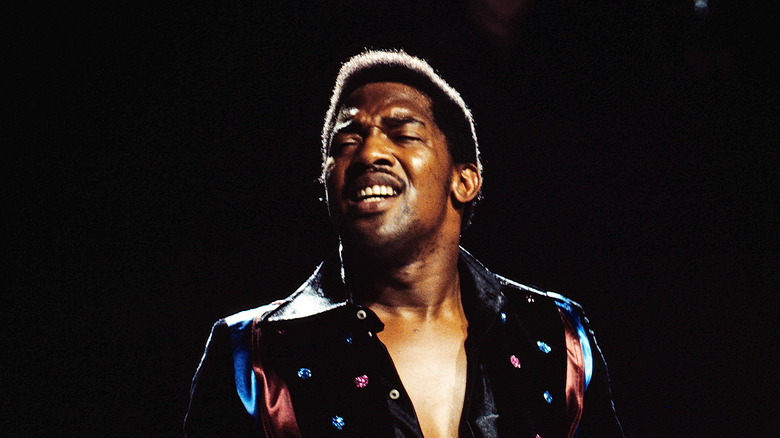 Edwin Starr in shiny suit singing on stage with black background