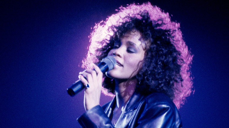 Whitney Houston singing into microphone on stage at Wembley Arena