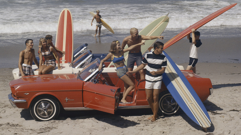 A 1960s beach scene with hot rod and surfboards