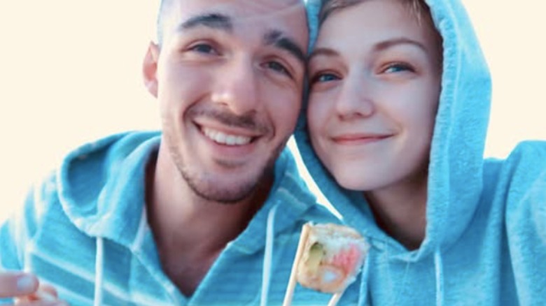 Brian Laundrie and Gabby Petito posing in hoodies with sushi