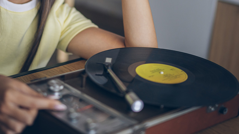 A person in a yellow shirt operating a vinyl record player