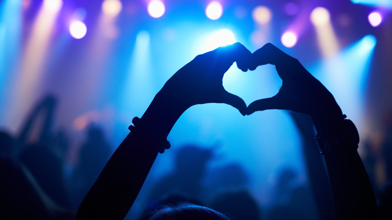 hands forming a heart at a concert