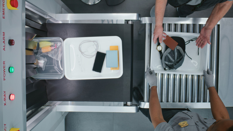 Agent scanning luggage at airport security scanner