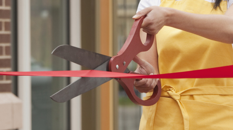 Woman cutting ribbon with oversized scissors