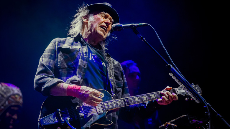Neil Young on stage singing and playing electric guitar