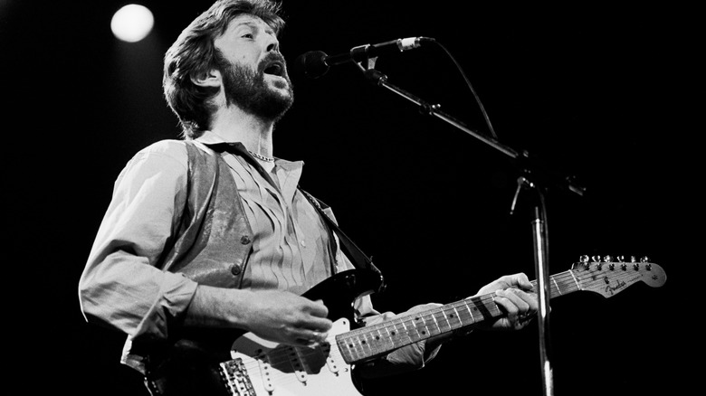 Eric Clapton sings and plays guitar on stage