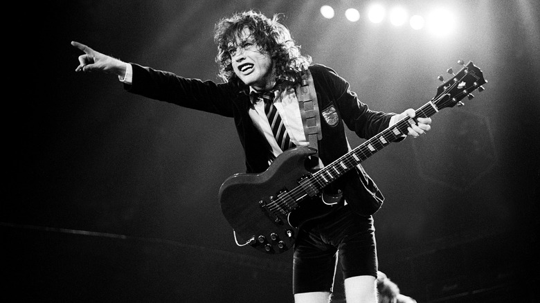 Angus Young playing guitar in school uniform on stage