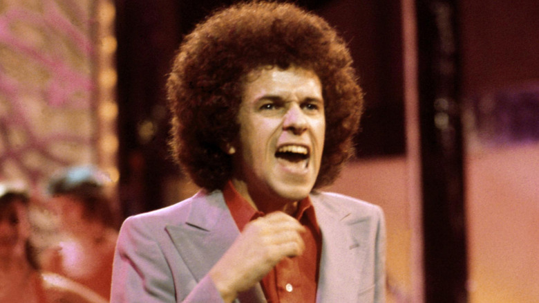 Leo Sayer singing and dancing in grey suit