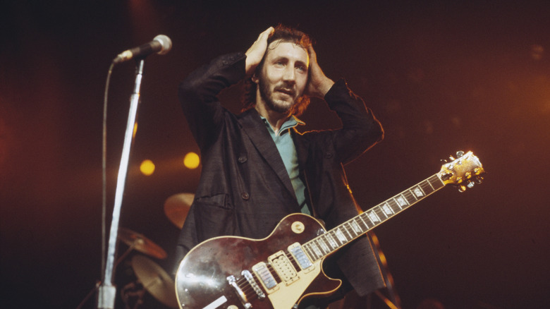 Pete Townshend holding hands to head on stage with guitar