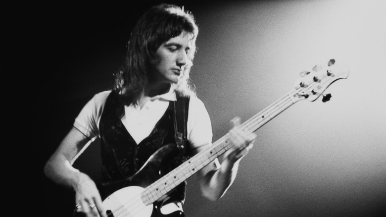 John Deacon onstage with bass