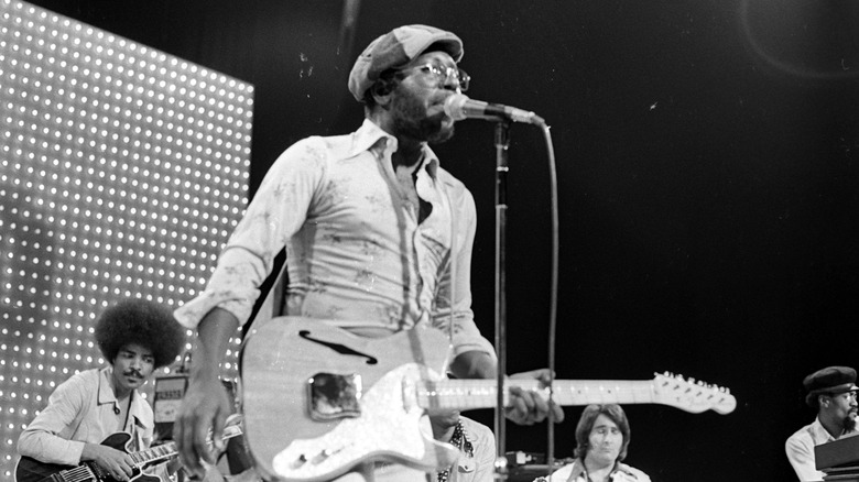 Curtis Mayfield on stage in hat with guitar