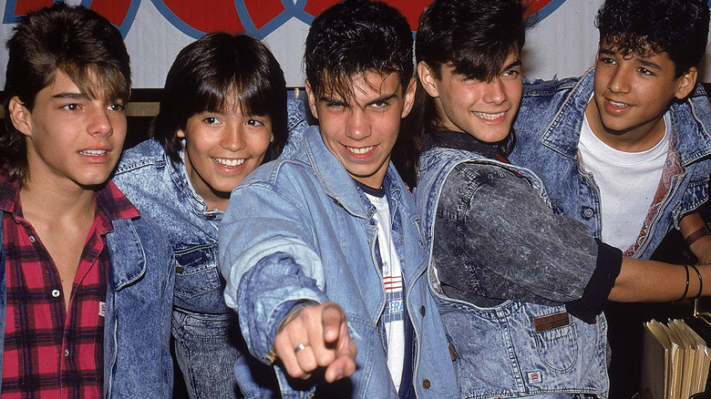 Menudo in jeans jackets and pointing at camera