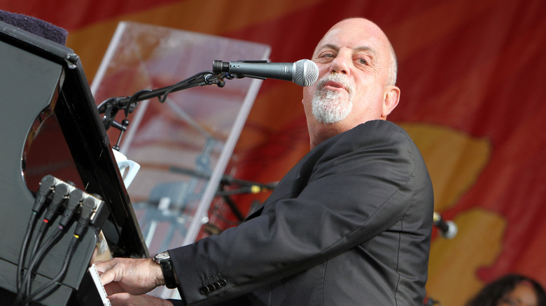 Billy Joel looking over his shoulder while playing the piano and singing