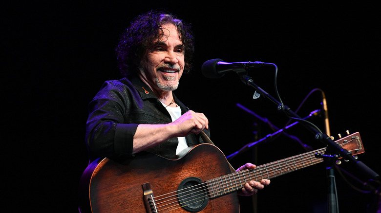 John Oates smiling with a guitar onstage