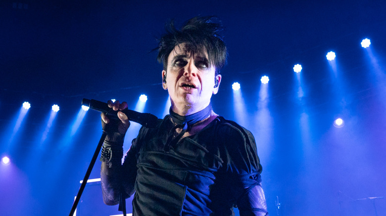 Gary Numan holding a microphone performing onstage