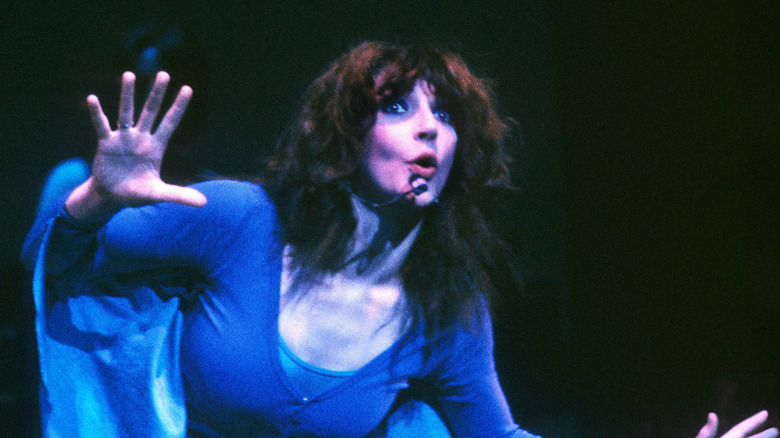 Kate Bush gesturing with both hands while performing onstage