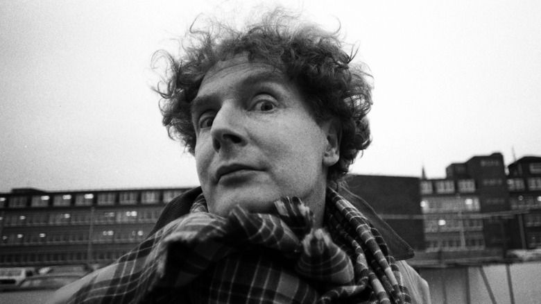 Malcolm McLaren posing for a photo wearing a plaid scarf