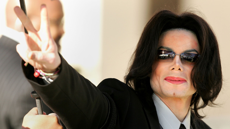 Michael Jackson giving a peace sign in sunglasses and long straight hair