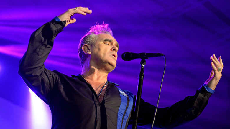Morrissey onstage under purple light with microphone