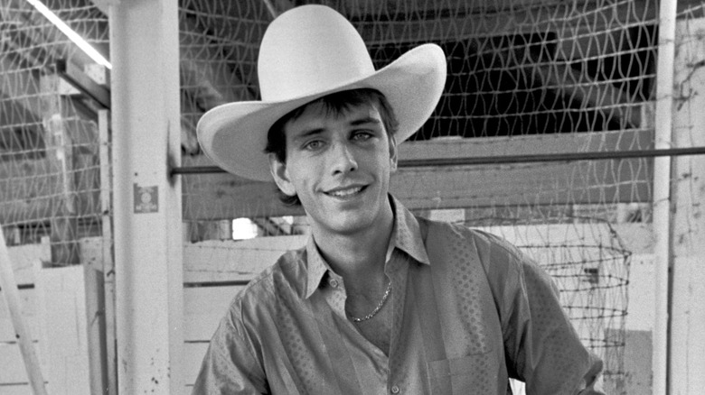 Lane Frost poses for photo with big hat in barn