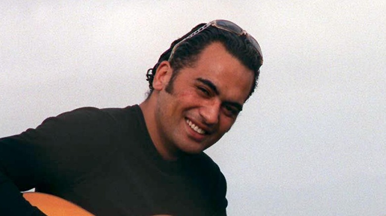 Pauly Fuemana of OMC smiling and holding guitar