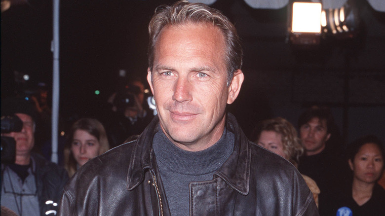 Kevin Costner grinning in leather jacket