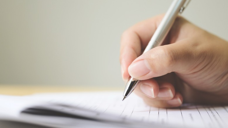 hand of man writing with a pen