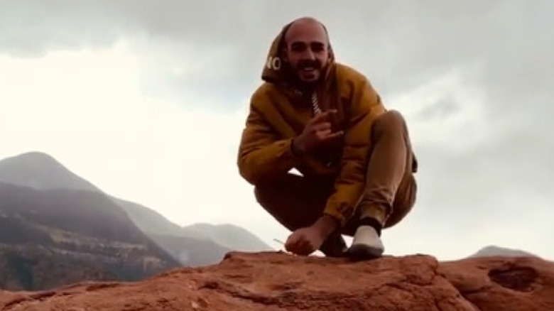 Brian Laundrie smiling and flashing the horns on a red rock