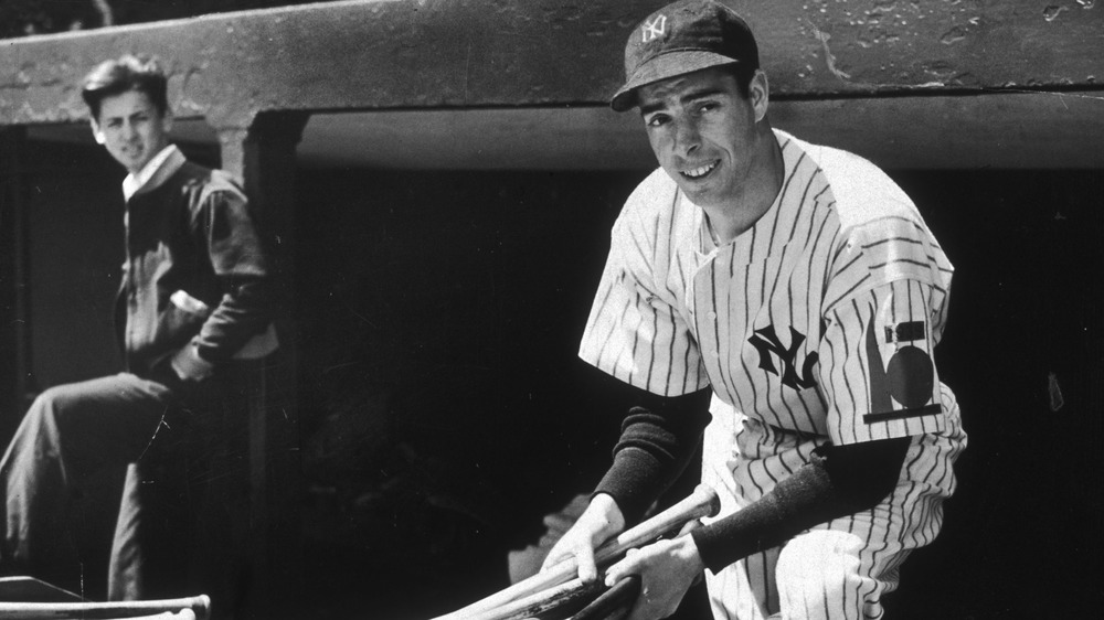 Joe DiMaggio holds baseball bats