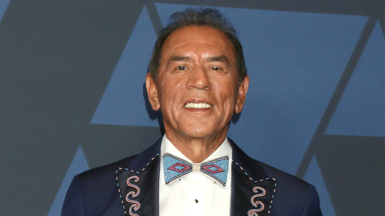 Wes Studi smiling and looking down at camera