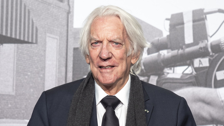Donald Sutherland wearing a suit, tie, and scarf
