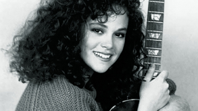 Rebecca Schaeffer holds a guitar smiling