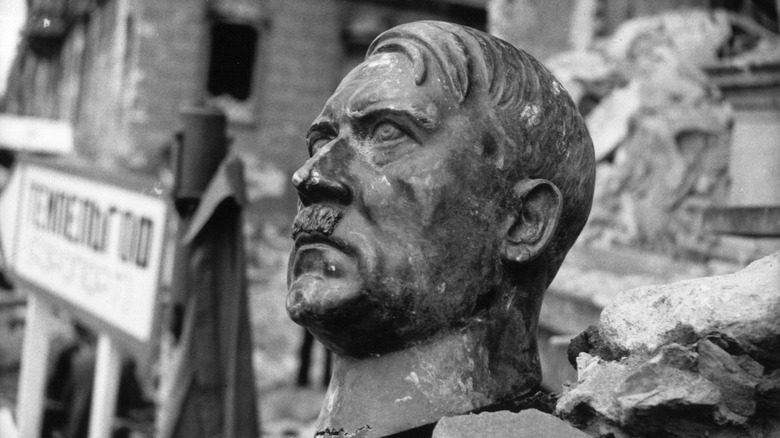 Broken bust of Adolf Hitler sits in a pile of rubble