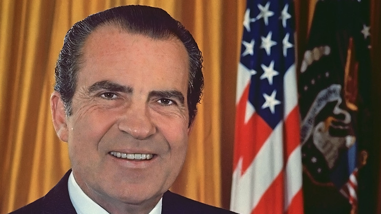 richard nixon smiling in front of flag