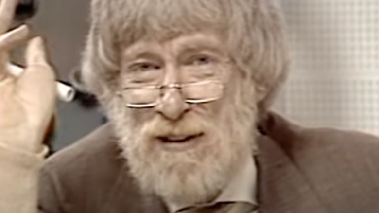 Alan Berg holding hand up wearing glasses