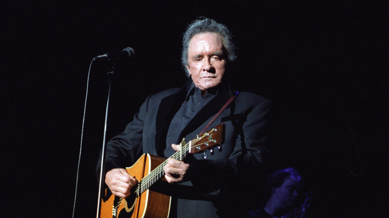 Johnny Cash playing guitar in dark suit on stage
