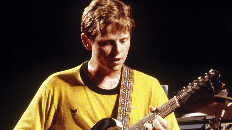 Ricky Wilson playing guitar on stage in yellow shirt