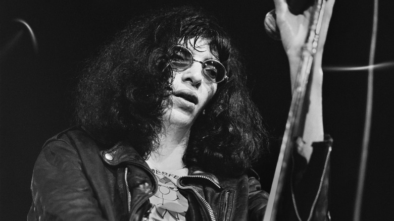 Joey Ramone wearing shaded glasses singing on stage