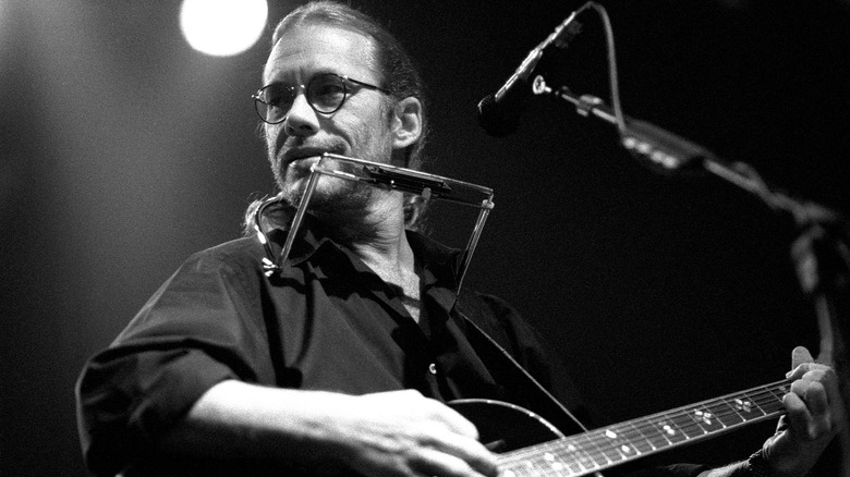 Warren Zevon playing guitar and harmonica on stage