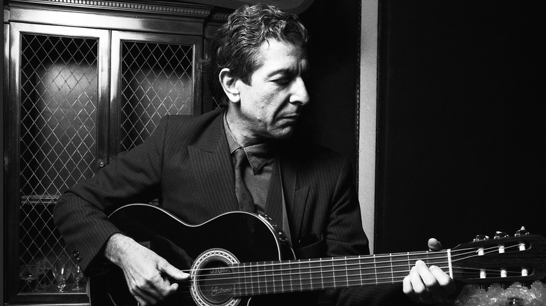 Leonard Cohen sat in suit playing guitar