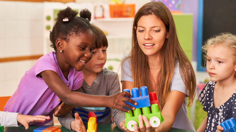 Kindergarteners play blocks with their teacher