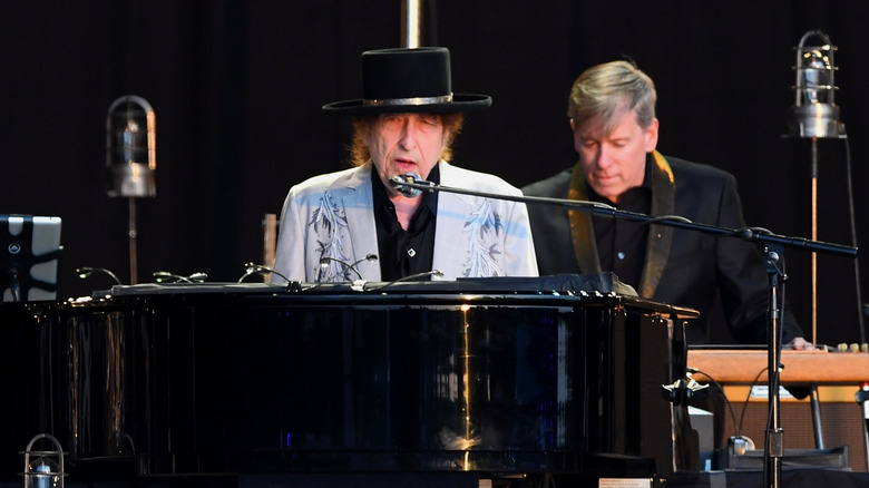 Bob Dylan at piano in gray suit and black hat