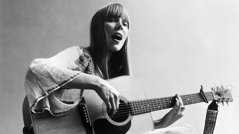 Joni Mitchell playing guitar on floor