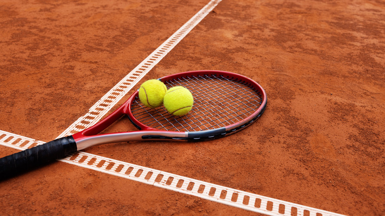 tennis racket and balls on clay court