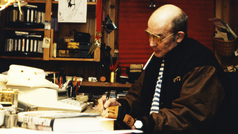 Hunter S Thomson writing at cluttered desk