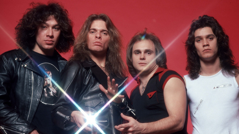 Original lineup of Van Halen posing for a portrait against a red background